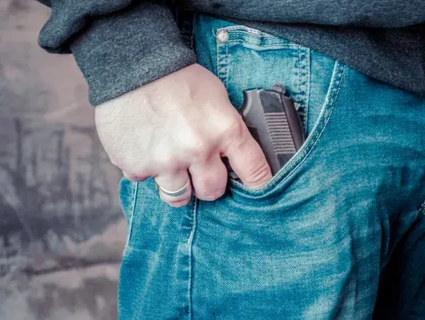 close up photo of a man holding the grip of a firearm still in his pocket, need a lawyer?